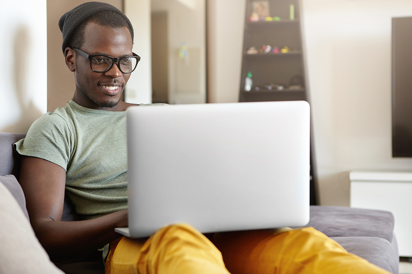 Man sitting on a couch using his laptop.